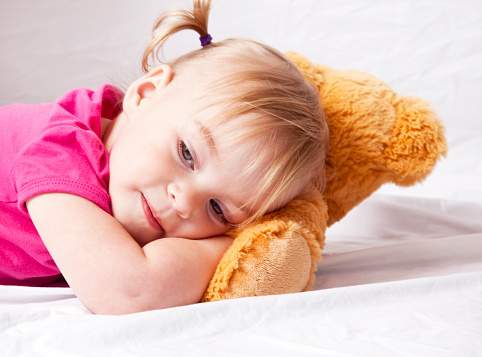 Small girl lays sleepy head on stuffed animal
