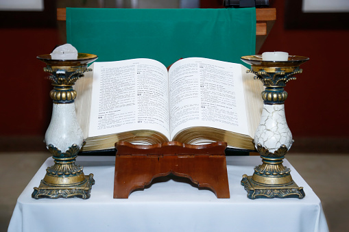 Holy Bible open on a wooden altar and candlestick on the side