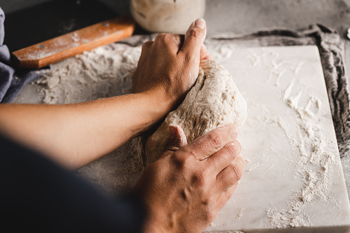 Point of view of a woman kneading bread dough. Focus on hands of a female making a dough for sourdough bread.