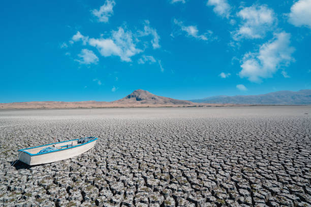 Aerial shot of single boat ship on dried, cracked, dry, drought lakebed surface Climate, lack of water, drone, global warming, texture lakebed stock pictures, royalty-free photos & images