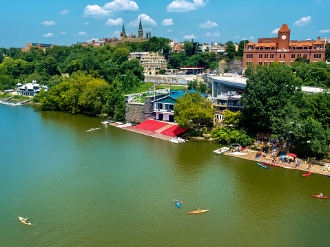 The waterfront at Georgetown in Washington D.C. is a busy hub of summertime water recreation and activity. This shot from Keys Bridge shows Georgetown University on horizon and private boat and canoe clubs along the shore of the Potomac River.