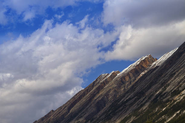 Treeless, soaring Canadian Rockies rock formations in the dramatic scenery of Icefields Parkway in Alberta. Horizontal with copy space on left in clouds.