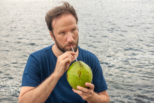 istock Man drinks coconut water beside the sea 1342976785