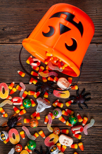 halloween jack o laterneneimer mit unterem rand aus verschütteten süßigkeiten über braunem rustikalem holz - stehlen verbrechen fotos stock-fotos und bilder