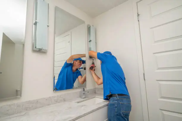 Handyman using a power drill to remove a cover from a light fixture