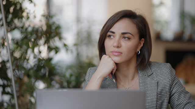 Arabian Hispanic woman working financial paperwork seated at workplace using laptop looks concentrated while makes task, prepare, check report having fruitful workday. Student learning process concept