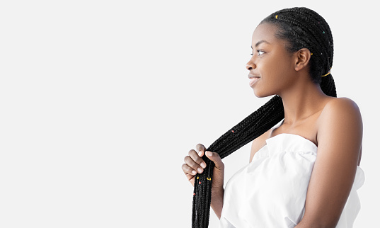 Hair treatment. African braids. Hairdressing fashion. Dreadlocks hairstyle. Salon hairdo. Profile of pretty Afro young woman with long stylish zizi thick locks on white copy space.