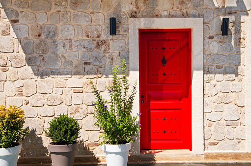Red door and potted plants at the entrance.