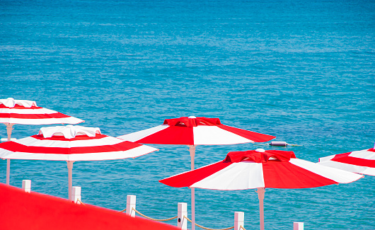 Sun Umbrellas on the Beach by the Sea on a bright sunny day against the backdrop of turquoise ocean water. Summer vacation concept. Relax and calmness. Space for text.