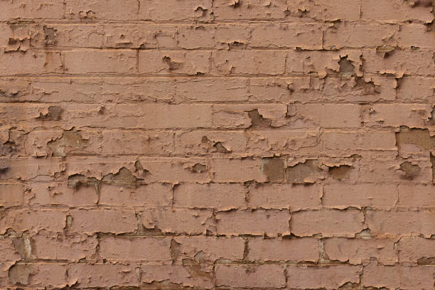 Section of an old brick wall with cracked and peeling paint.