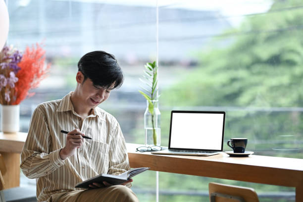 istock Smiling young man entrepreneur sitting in bright office and making notes on notebook. 1343082640