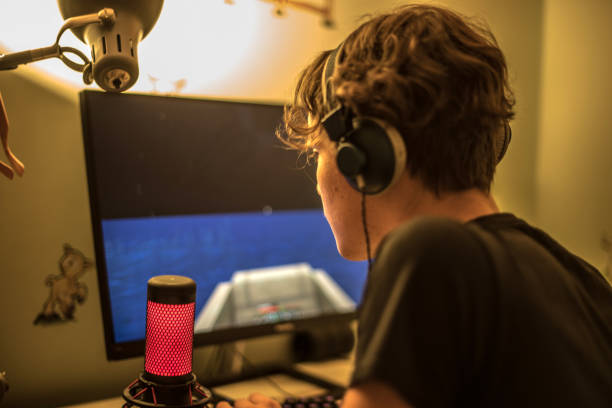 istock Teenager Boy Playing Multiplayer Video Game on Computer Wearing Headphones 1343085918