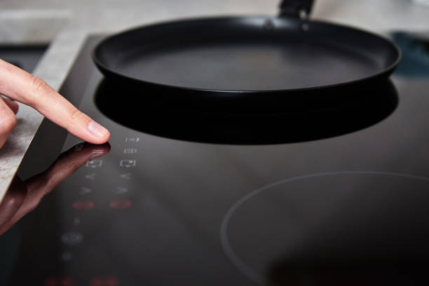 istock Woman hand turns on modern induction stove in the kitchen 1343086784