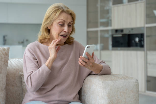 istock An enthusiastic old woman using a smartphone, impressed by social networks, sitting on the sofa in the living room 1343089990