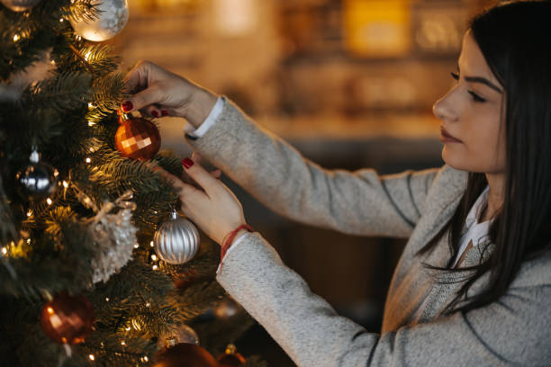 istock Beautiful young woman decorating Christmas tree 1343096191