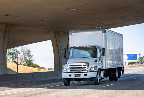 istock Compact medium power rig semi truck with box trailer running on the highway road under the bridge 1343098639