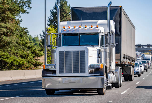 istock White classic big rig semi truck transporting cargo in covered dry van semi trailer  running in front of another traffic 1343098708