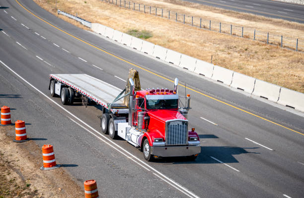 istock Classic powerful industrial red big rig semi truck transporting cargo fastened on flat bed semi trailer running on the divided highway road 1343099828