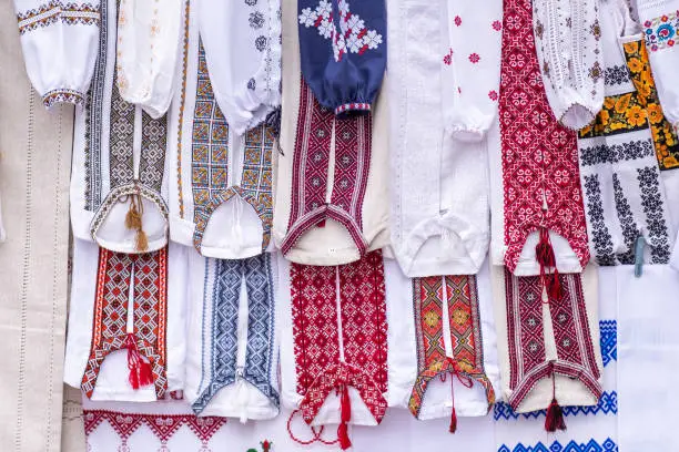 Photo of Many Ukrainian national clothes - embroidered shirts hang on counter, sold in the market.