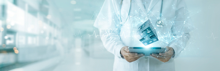 Doctor using tablet on digital medical cube interface icon. Digital healthcare and network connection on hologram. Technology and Innovation. Medical healthcare research and development concept .