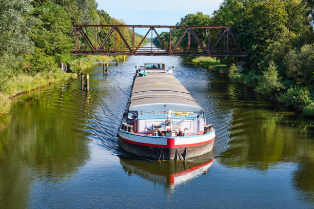 istock cargo canal ship passes under an old iron bridge on a sunny autumn day, reflections are to be seen in the water, canal system in the outskirts of Berlin Germany 1343102210