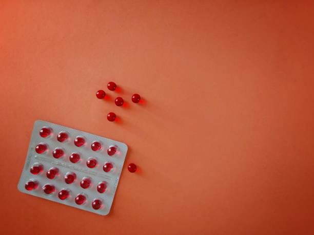 Pills blister. Red vitamin E close up Remedial drug capsules on a bright orange background. stock photo