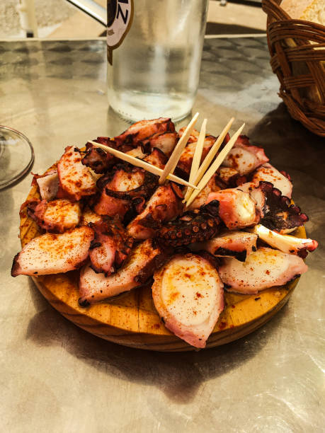 pulpo gallego en plato de madera sobre mesa de bar - spanish cuisine fotografías e imágenes de stock