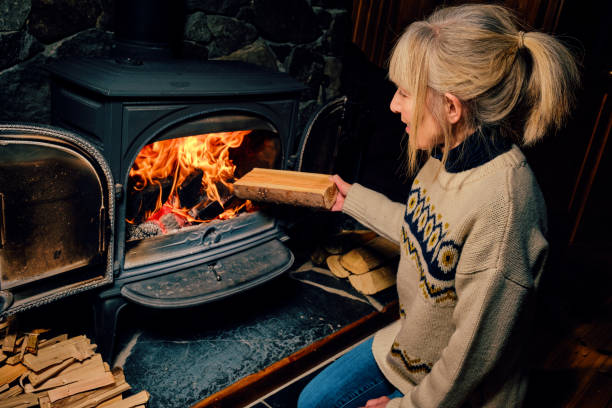 Wood burning stove Woman putting a well dried log into a glowing wood burning stove. wood burning stove stock pictures, royalty-free photos & images