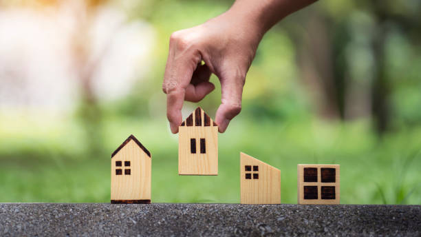 istock Closeup man hand choosing house model on nature background 1343120324