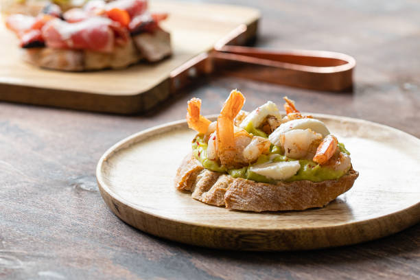 assorted bruschetta with shrimp, avocado guacamole, mozzarella cheese, sun-dried tomatoes, prosciutto in high key style on wooden table background. - mozzarella tomato sandwich picnic imagens e fotografias de stock