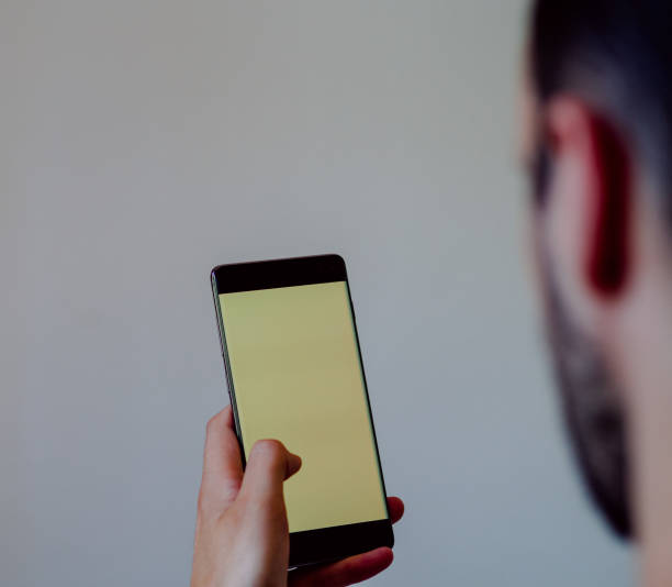 istock Unrecognizable man from behind using a mobile with a screen to place a banner 1343123902