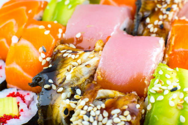 Tasty Colorful assorted Set of different type Sushi. Dinner in Japanese style. Healthy food. Filadelfia and Maki sushi rolls with Avocado, Tuna, Salmon, fish and Prawns. Close up view. Wallpaper.
