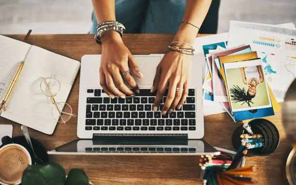 Photo of Shot of an unrecognisable businesswoman using a laptop while working remotely