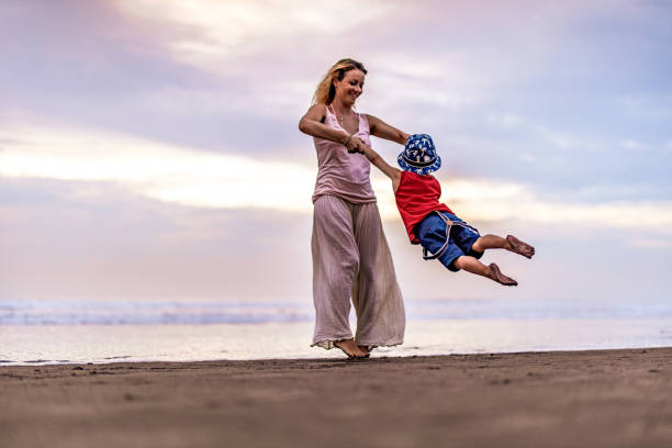 istock Playful mother having fun while spinning her son on the beach. 1343153066
