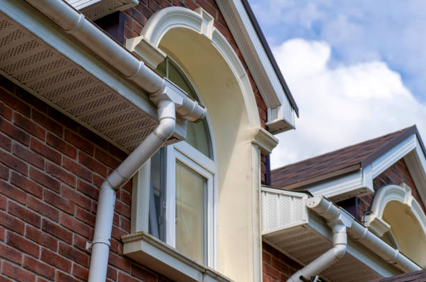 Closeup view of old white gutter system with soffit vent, window with white frame, gutter guard, downspout, decorative trim molding, on corner of brick luxury house stock photo