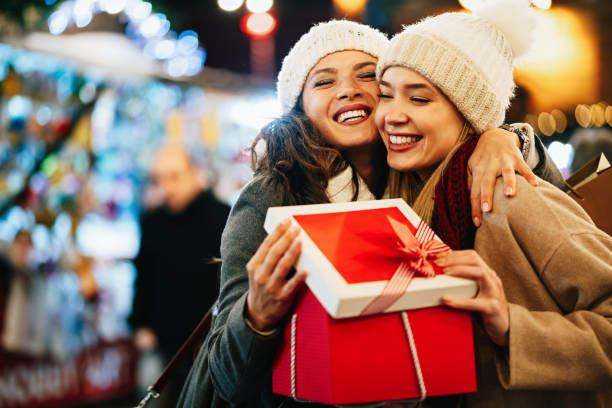 счастливые подруги обмениваются рождественским подарком. счастье люди друзья шоппинг рождественская концепция - sale relationships loving indoors стоковые фото и изображения