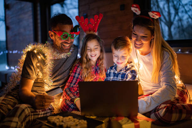 famiglia felice che si diverte nello shopping online alla vigilia di natale a casa. - christmas shopping internet family foto e immagini stock