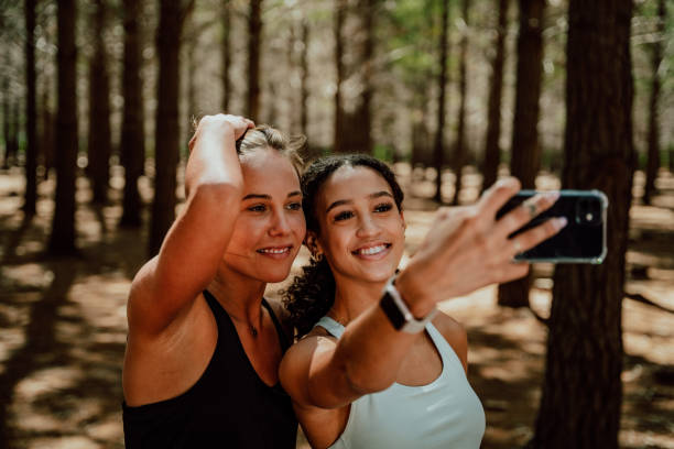 istock two friends smiling for selfie on cellular device standing in forest 1343161814