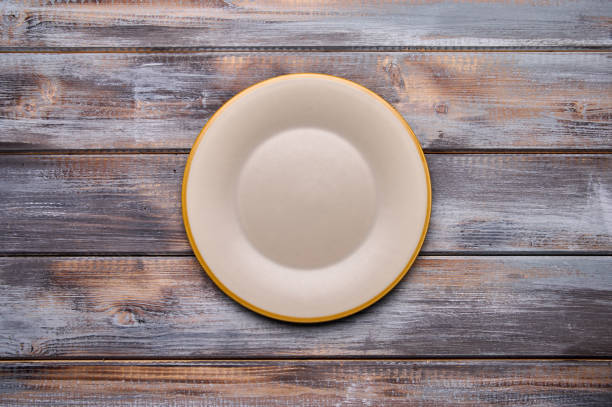 istock Light empty plate with brown edge on from boards wooden background, top view 1343163499
