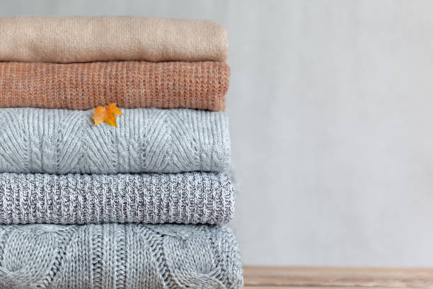 istock Pile of cozy knitted sweaters on a neutral background. Warm concept 1343164115