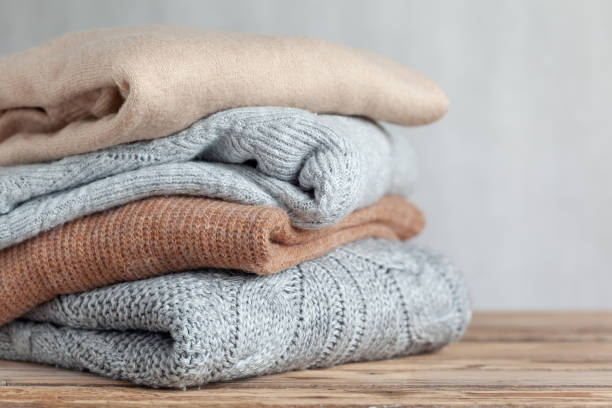 istock Pile of cozy knitted sweaters on a neutral background. Warm concept 1343164180