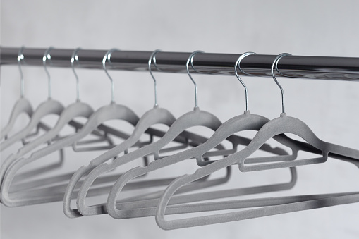 Modern velvet grey empty hangers on neutral wall background.