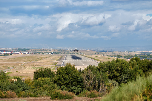 Madrid, Spain; 09-25-2021: Runway and terminal of Madrid Barajas airport, in which we can see an Airbus A321 of the Iberia Express airline taking off with a cloudy sky