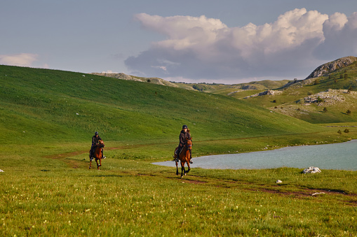 Young tourist couple enjoying horseback riding by the lake