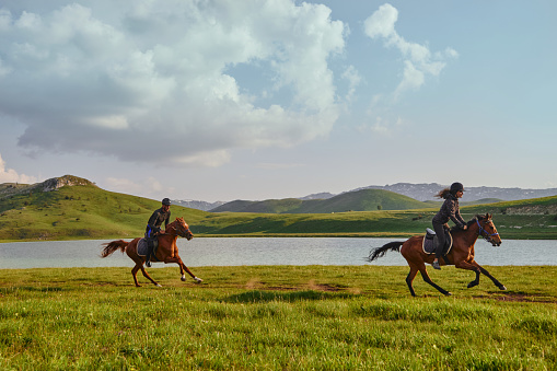 Young tourist couple enjoying horseback riding by the lake