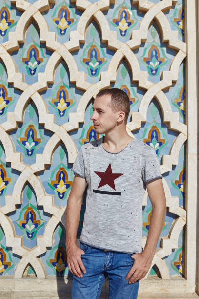 ritratto di un uomo sullo sfondo della moschea di hassan ii in marocco, casablanca - clothing east africa color image colors foto e immagini stock
