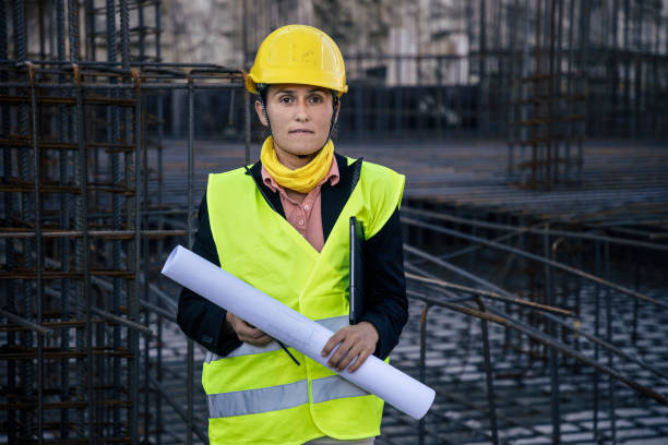 Portrait of female engineer working on construction site with tablet, checking the work progress.