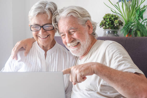 istock Beautiful senior couple  using laptop computer laughing. Serene elderly people enjoying technology and social 1343189604
