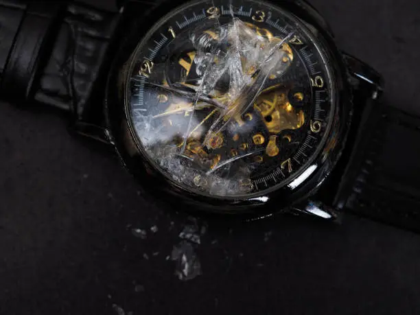 Close up shot of black automatic wristwatch that has a broken glasses. The watch equipped with leather strap
