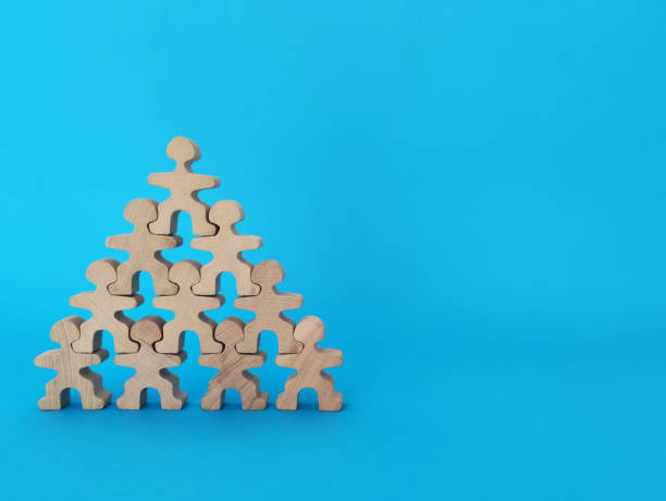 Teamwork and cooperation concept, wooden people standing shoulder to shoulder forming a pyramid Teamwork and cooperation concept, wooden people standing shoulder to shoulder forming a pyramid corporate culture stock pictures, royalty-free photos & images